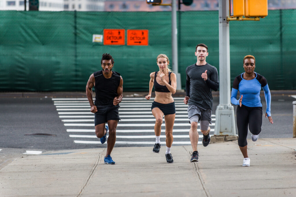 Multi-ethnic runners running down a street in Brooklyn for a previous Brooklyn Half Marathon