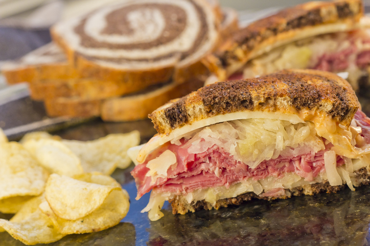 A Reuben sandwich with a heaping pile of pastrami, topped with sauerkraut, Swiss cheese, and house-made Reuben sauce. This and more served at A Taste of Katz's.