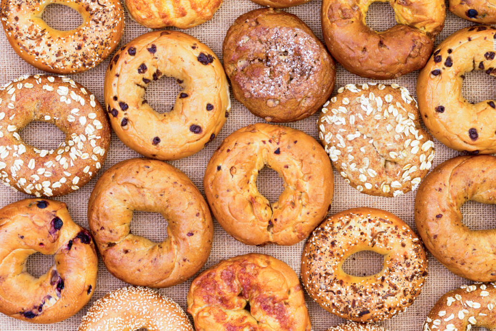 Showcasing the history of the bagel, a variety of everything, blueberry, strawberry, oat, sesame, egg, raisin, and onion bagels are on display.