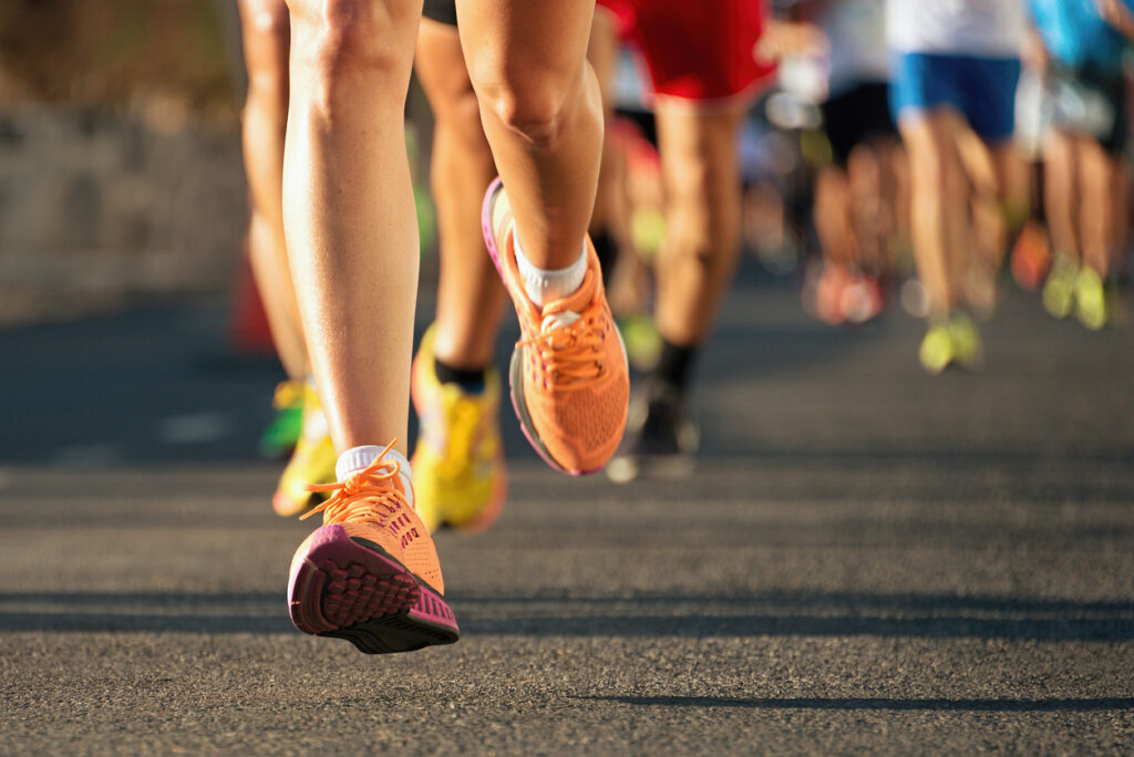 Orange and pink sneakers and a female's legs are in focus while running at sunset.