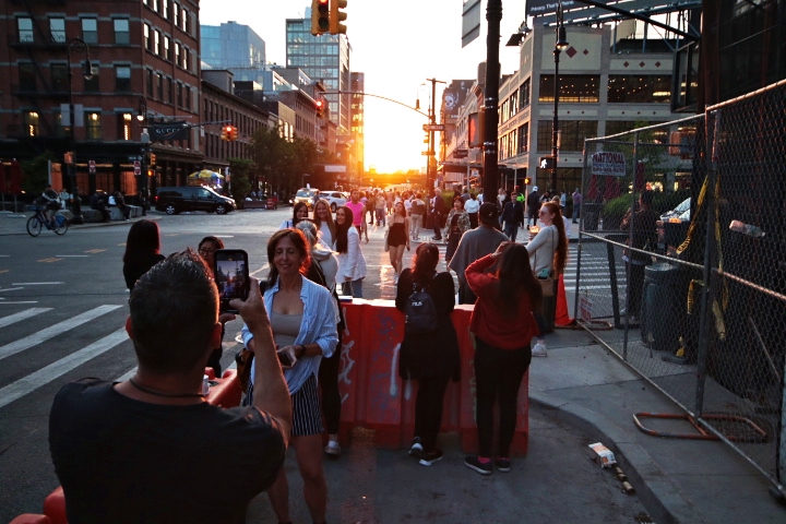 People are gathering to watch Manhattanhenge and are taking pictures.